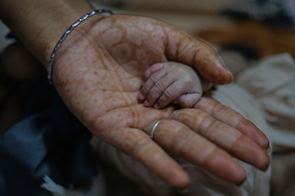 Antima Kumari holds the hand of her newborn nephew at their house in Gurugram, a satellite city of New Delhi, India, Friday, Aug. 8, 2025. (AP Photo/Manish Swarup)