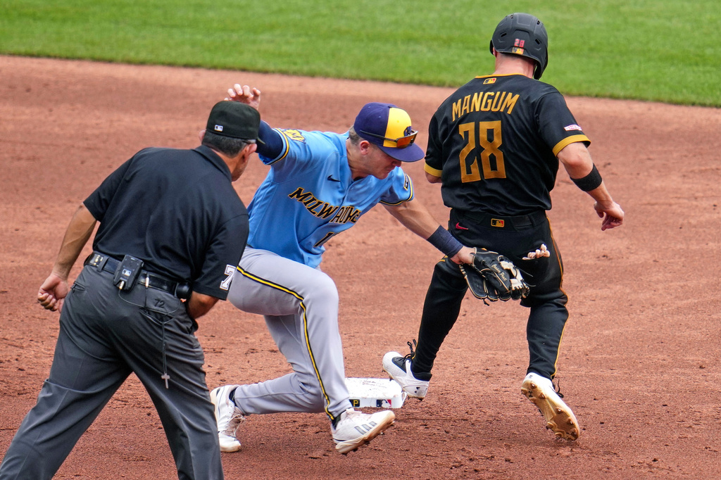 Pittsburgh Pirates' Jake Mangum (28) is tagged out by Milwaukee Brewers shortstop Cooper Pratt, center, with umpire Alfonso Marquez watching during the third inning of the first game of a baseball doubleheader in Pittsburgh, Saturday, July 11, 2026. (AP Photo/Gene J. Puskar)