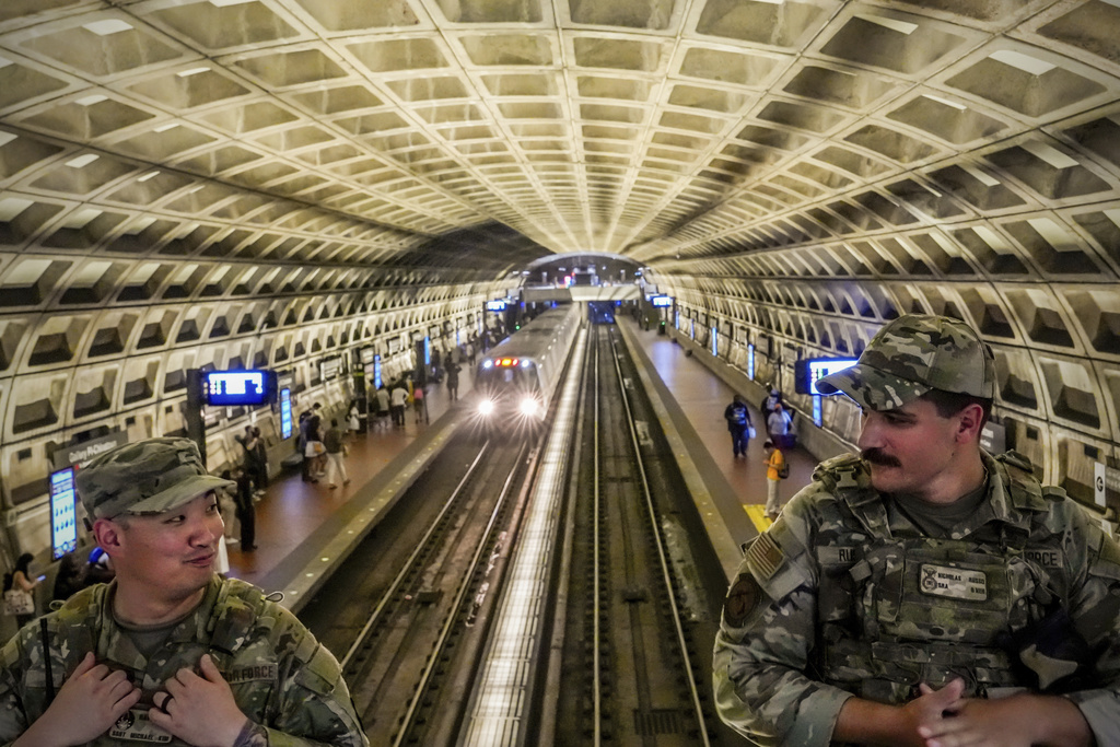 A train passes through as District of Columbia National Guardsmen patrol inside the Gallery Place-Chinatown Metro Station, Sunday, Aug. 17, 2025, in Washington. (AP Photo/Julia Demaree Nikhinson)