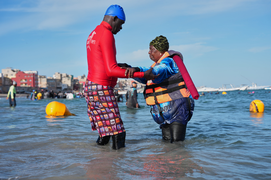 FILE - An instructor assists a participant with limited mobility out of the ocean after an aquatic therapy session in Dakar, Senegal, Saturday, Dec. 13, 2025. (AP Photo/Misper Apawu, File)