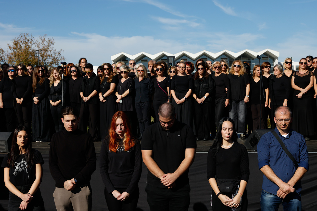 People observe 16 minutes of silence in memory of the victims, outside the train station, on the first anniversary of the disaster that killed 16 people, in Novi Sad, Serbia, Saturday, Nov. 1, 2025. (AP Photo/Marko Drobnjakovic)