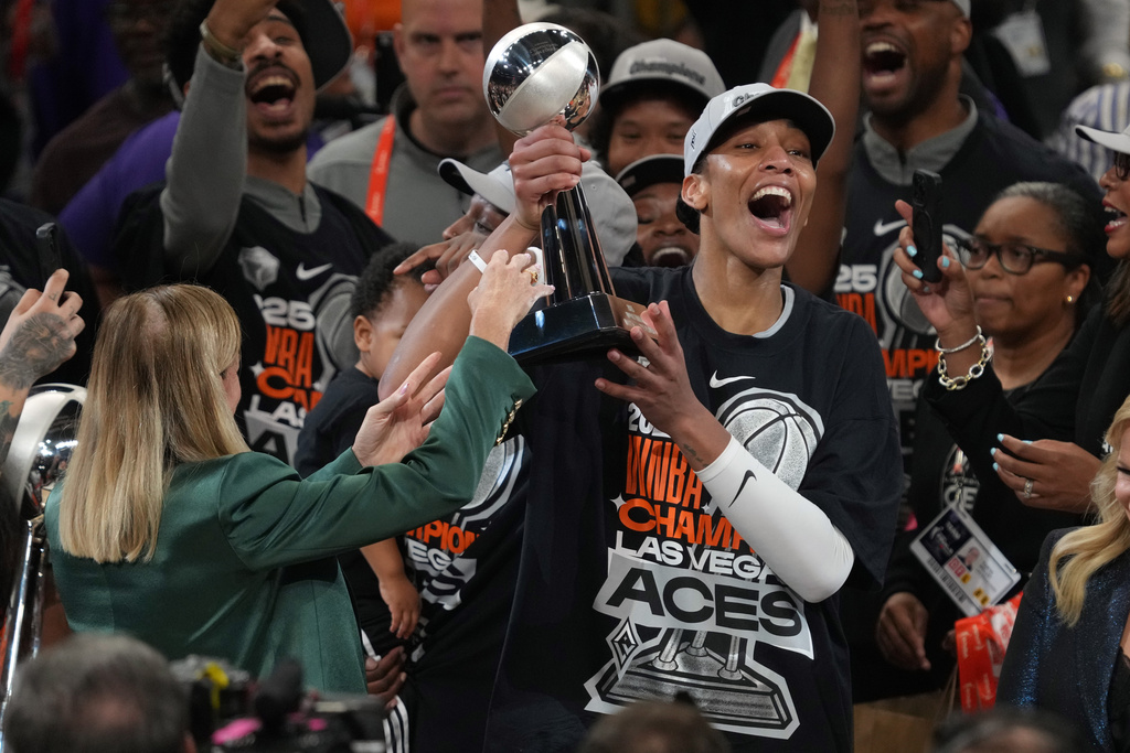 Las Vegas Aces center A'ja Wilson, center right, holds up her MVP trophy after Game 4 of the WNBA basketball finals against the Phoenix Mercury, Friday, Oct. 10, 2025, in Phoenix. (AP Photo/Rick Scuteri)