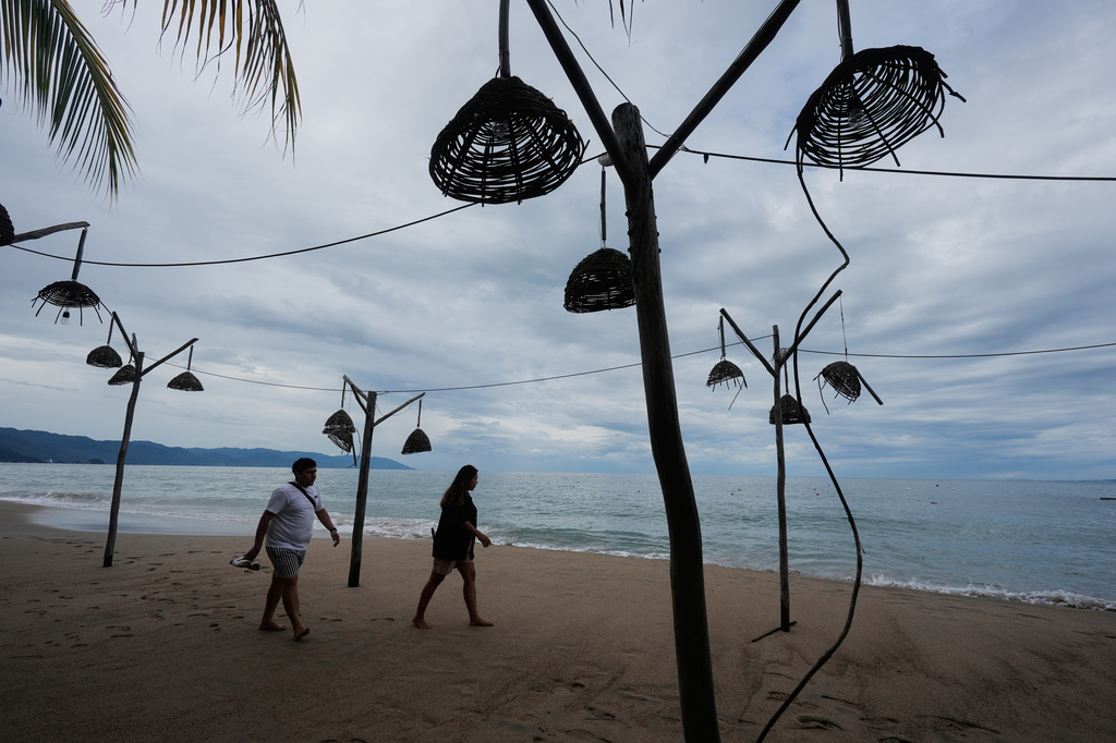 People walk on the beach after the passing of Hurricane Simon in Puerto Vallarta, Mexico, Monday, Oct. 12, 2026. (AP Photo/Fernando Llano)