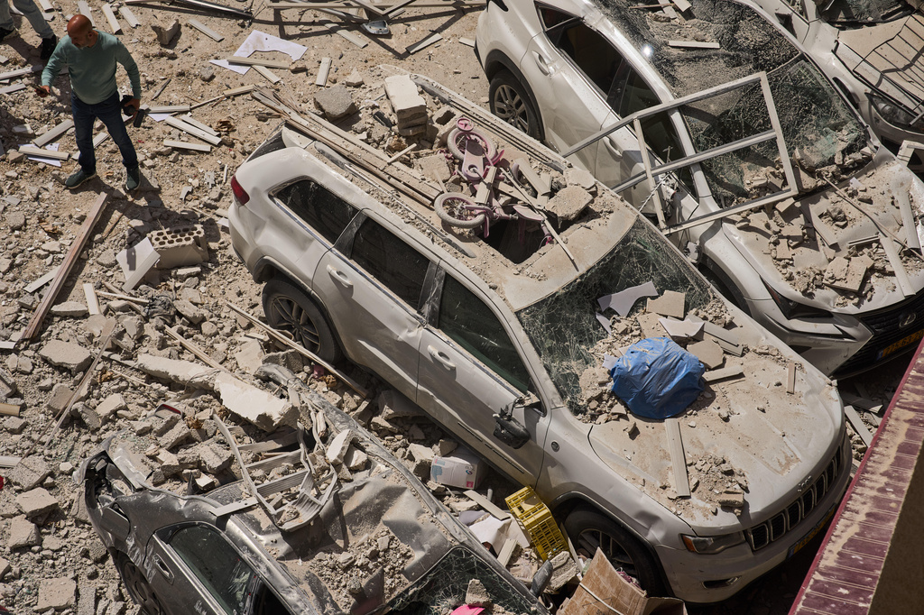 A man inspects the damage to cars and an apartment building struck by an Iranian missile in Ramat Gan, Israel, Monday, April 6, 2026. (AP Photo/Oded Balilty)