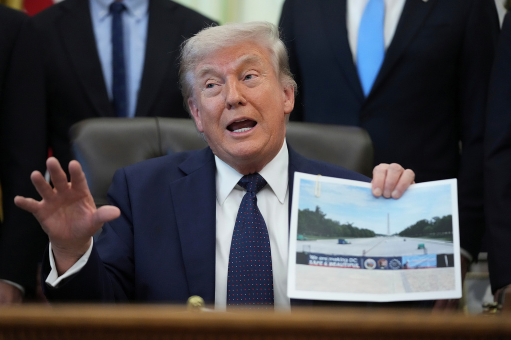 President Donald Trump holds a picture of the Lincoln Memorial Reflecting Pool during an event on health care affordability in the Oval Office at the White House, Thursday, April 23, 2026, in Washington. (AP Photo/Mark Schiefelbein)