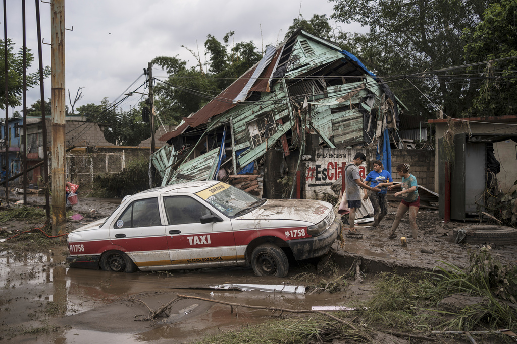 Neighbors gather around a damaged house after heavy rainfall in Poza Rica, Veracruz state, Mexico, Saturday, Oct. 11, 2025. (AP Photo/Felix Marquez)