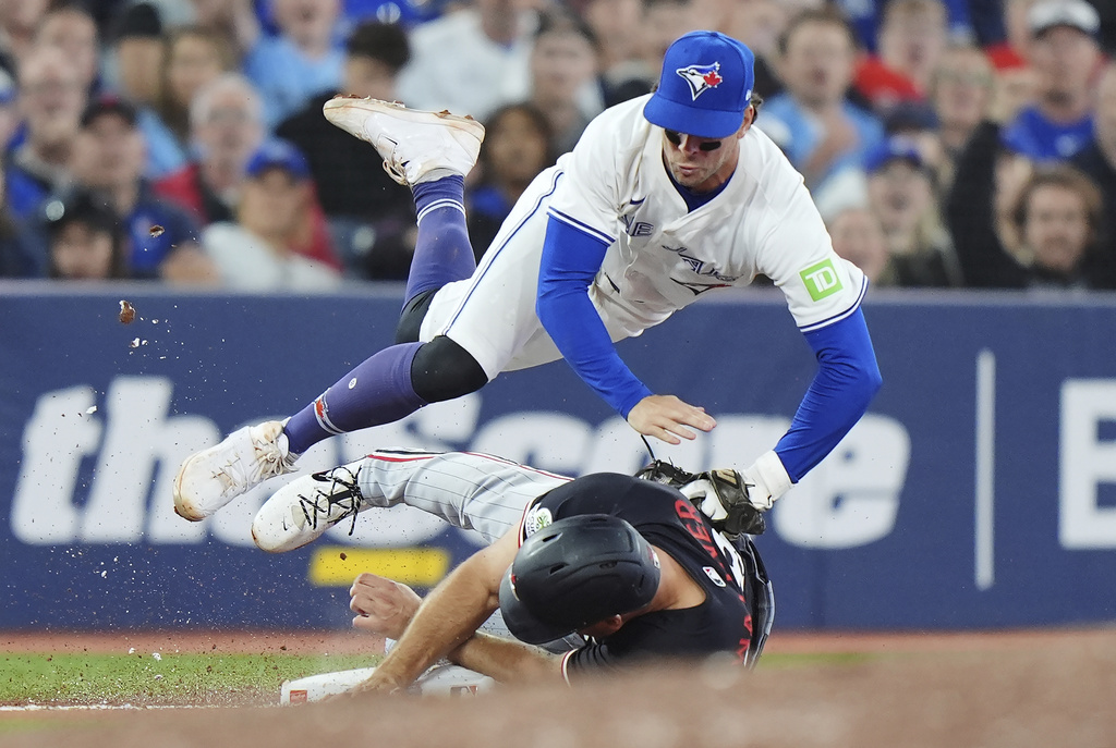 Toronto Blue Jays third baseman Ernie Clement (top) tags out Minnesota Twins' Matt Wallner (38) at third base during eighth inning MLB baseball action in Toronto on Tuesday, August 26, 2025. (Frank Gunn/The Canadian Press via AP)