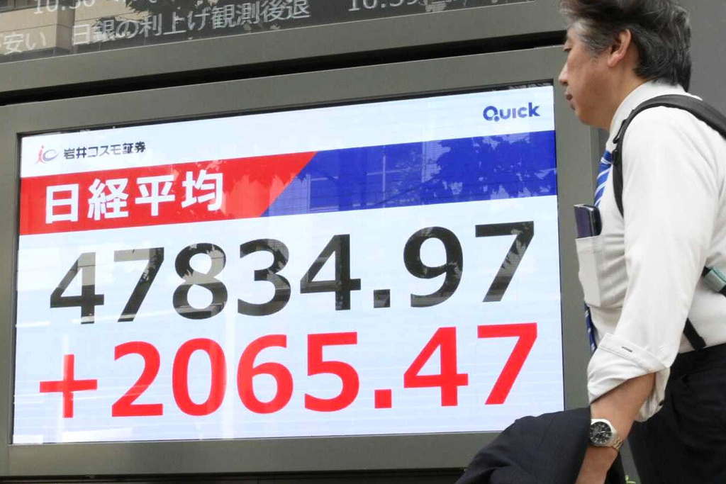 People walks by an electronic stock board showing Japan's Nikkei 225 index at a securities firm in Tokyo, Monday, Oct. 6, 2025. (Kyodo News via AP)