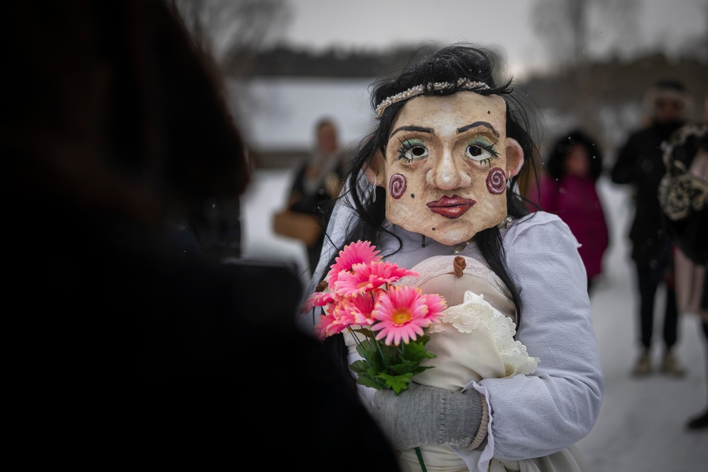 A reveller wearing traditional carnival masks takes part in Shrovetide celebrations in the village of Rumsiskes, some 89 kilometers (56 miles) north of Vilnius, Lithuania, Saturday, Feb. 14, 2026. (AP Photo/Mindaugas Kulbis)