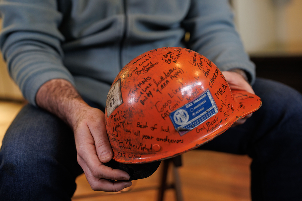 Former U.S. Steel worker Jonathan Ledwich holds his old hard hat at the pizza shop he now owns in Trafford, Pa., on Monday, Dec. 15, 2025. (Quinn Glabicki/Pittsburgh's Public Source via AP)