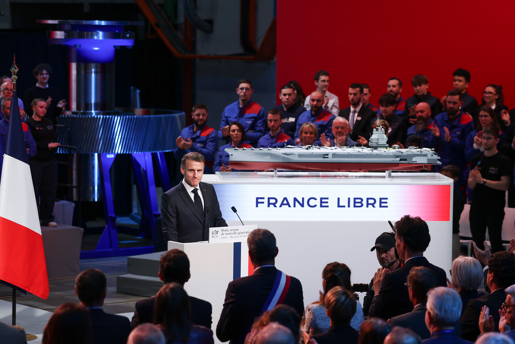 French President Emmanuel Macron stands next to the model of a ship named "France Libre", as he delivers a speech during his visit to the construction site of Naval Group Nantes-Indret, where the next generation of French aircraft carrier is under construction, in Indret, France, Wednesday, March 18, 2026. (Gonzalo Fuentes/Pool Photo via AP)