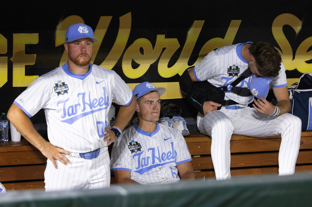 From left, North Carolina undergraduate assistant coach Kyle Datres, Macon Winslow and Olin Johnson sit in the dugout following their loss to Oklahoma in Game 3 of the NCAA College World Series baseball finals in Omaha, Neb., Monday, June 22, 2026. (AP Photo/Rebecca S. Gratz)