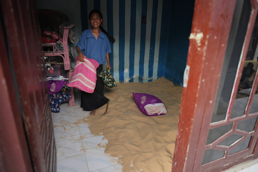 A girl holds a pillow inside a bedroom which has sand for people to sleep on, in Legung Timur village in Sumenep on Madura Island, Indonesia, Tuesday, Sept. 9, 2025. (AP Photo/Dita Alangkara)