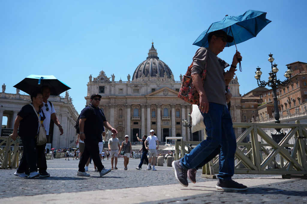 People shade from the sun under umbrellas as they walk through St. Peter's Square at the Vatican, Thursday, June 25, 2026. (AP Photo/Andrew Medichini)