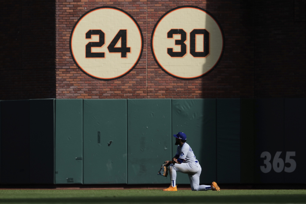 Los Angeles Dodgers right fielder Teoscar Hernández kneels in the outfield as he watches a play being reviewed during the ninth inning of a baseball game against the San Francisco Giants, Sunday, Sept. 14, 2025, in San Francisco. (AP Photo/Godofredo A. Vásquez)