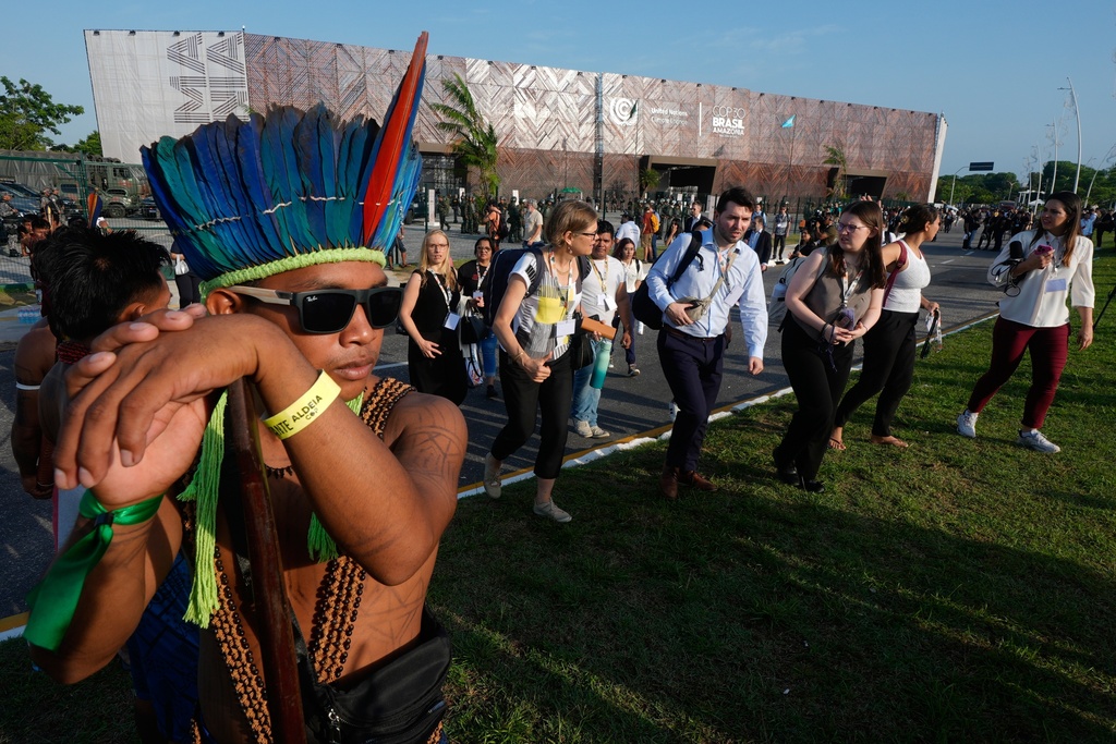 An Indigenous group blocks an entrance to the COP30 U.N. Climate Summit as attendees walk around them, Friday, Nov. 14, 2025, in Belem, Brazil. (AP Photo/Fernando Llano)