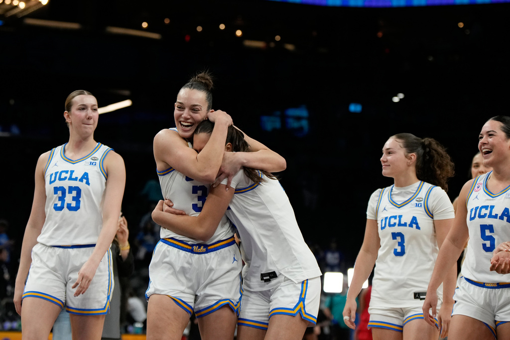 UCLA forward Angela Dugalic, second from left, embraces UCLA guard Lena Bilic (9) after defeating Texas in a women's NCAA college basketball tournament semifinal game at the Final Four, Friday, April 3, 2026, in Phoenix. (AP Photo/Ross D. Franklin)