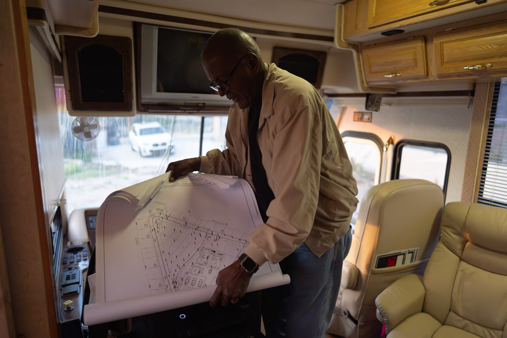 Ellaird Bailey, who lives in an RV on the property where his home was destroyed in the Eaton Fire, looks at building plans, Dec. 12, 2025, in Altadena, Calif. (AP Photo/Jae C. Hong)