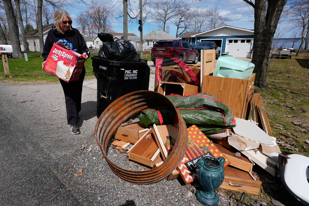 Diane Peterman throws away damaged belongings from recent floods outside their home at Black Lake on Wednesday, April 29, 2026, in Grant Township, Mich. (AP Photo/Paul Sancya)