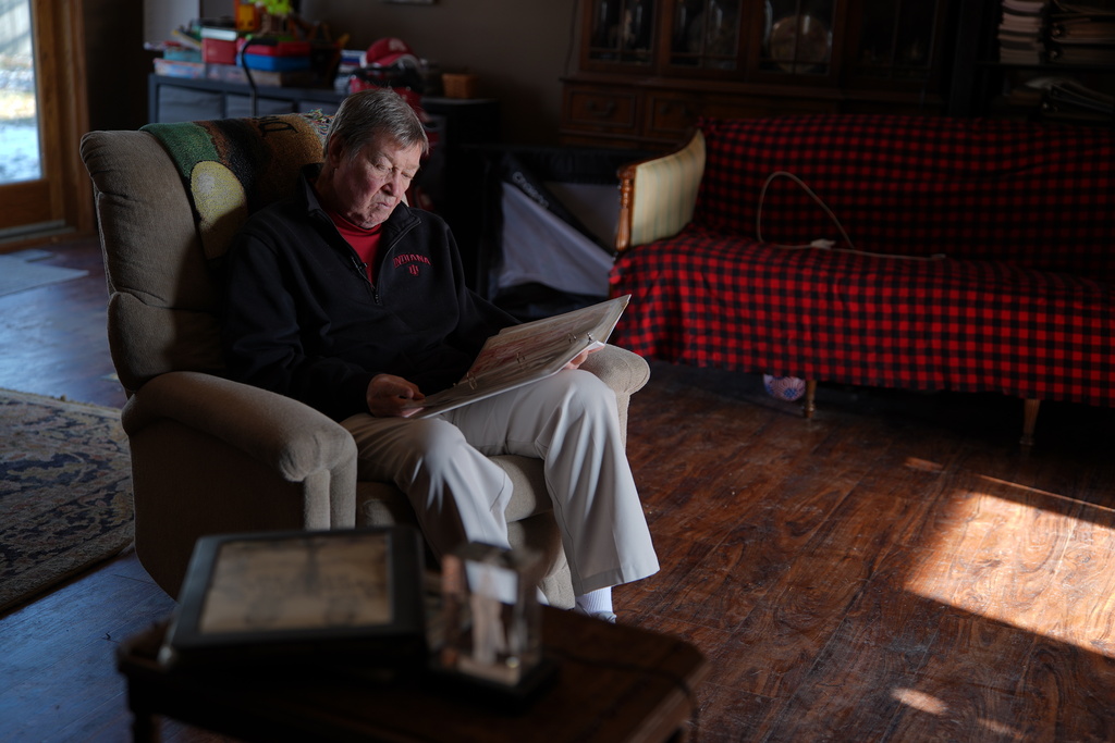 Bill Murphy, 77, an Indiana football fan, looks through vintage sports programs in a photo album at his home in Greenfield, Ind., Wednesday Dec. 17, 2025. (AP Photo/Obed Lamy)