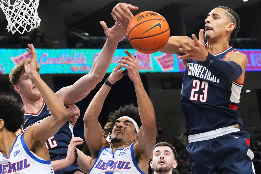 UConn forward Jayden Ross, right, battles for a rebound with DePaul guard RJ Smith, center, and UConn center Eric Reibe, left, during the first half of an NCAA college basketball game in Chicago, Sunday, Dec. 21, 2025. (AP Photo/Nam Y. Huh)