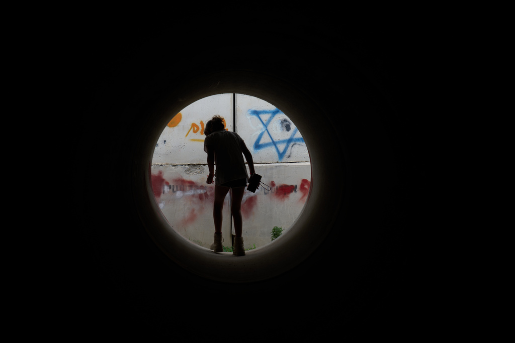 A girl walks inside a cement pipe turned into a bomb shelter as air raid sirens warn of incoming Iranian missile strike in Michmoret, Israel, Saturday, March 14, 2026. (AP Photo/Ariel Schalit)
