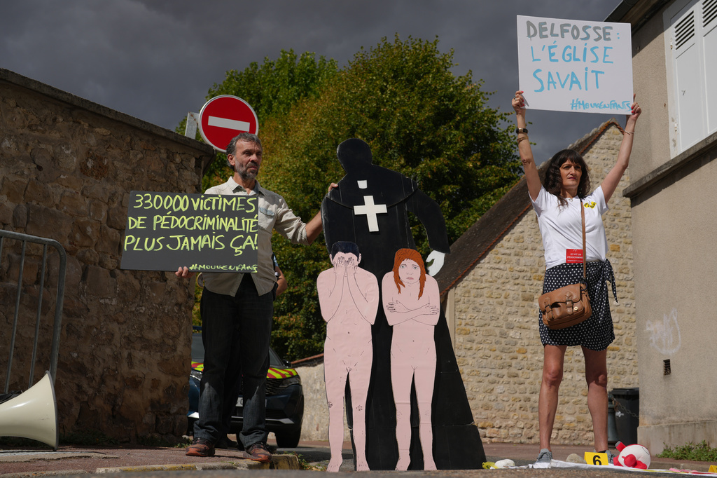 Activists fighting child abuse stage a protest near the home of a former Catholic priest suspected of sexually assaulting dozens of children, in Etrechy, outside Paris, Wednesday, Sept 16, 2026, Placards read from the left: '330,000 victims of child sexual abuse, never again' and Delfosse, the church knew'. (AP Photo/Thibault Camus)