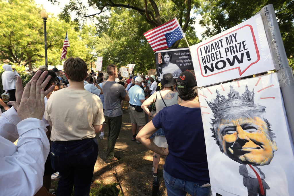 Activists carry signs during a protest against President Donald Trump's federal takeover of policing of the District of Columbia, Saturday, Aug. 16, 2025, in Washington. (AP Photo/Alex Brandon)