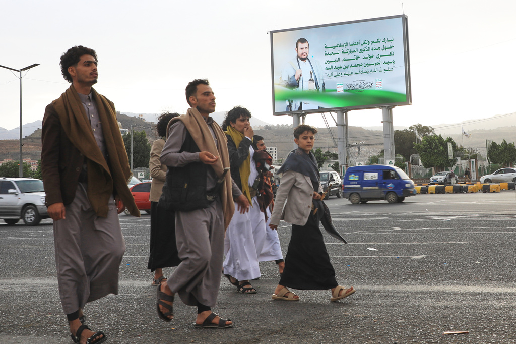 People walk under a billboard showing Houthi leader Abdul Malik al-Houthi with a phrase from the Islamic book Quran that reads in Arabic; "In the bounty of Allah and in His mercy - in that let them rejoice; it is better than what they accumulate" in Sanaa, Yemen, Sunday, Sept. 6, 2026. (AP Photo/Osamah Abdulrahman)