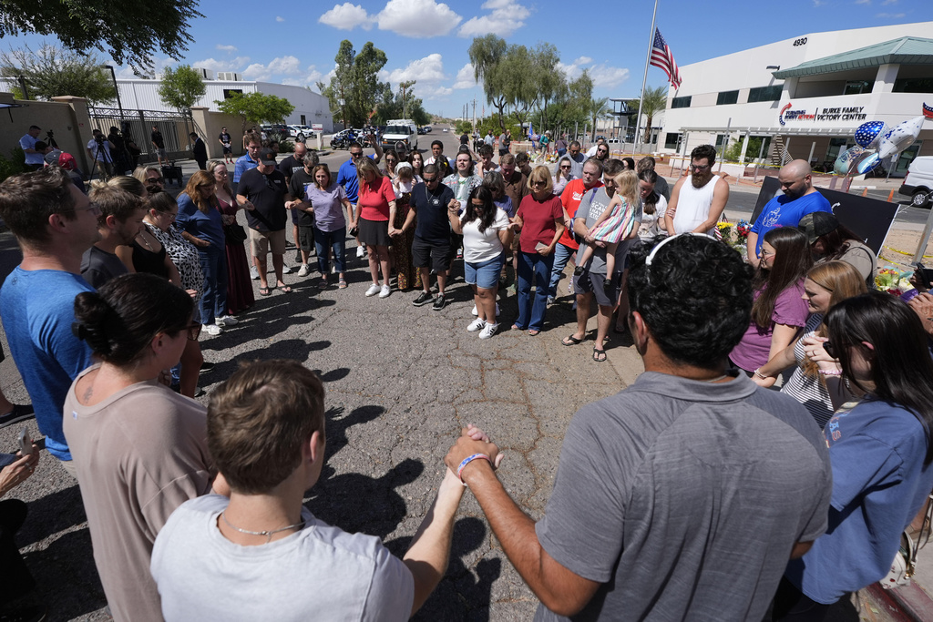 Well-wishers pray at a makeshift memorial set up at Turning Point USA headquarters after the shooting death at a Utah college on Wednesday of Charlie Kirk, the 31-year-old founder and CEO of the organization, Thursday, Sept. 11, 2025, in Phoenix. (AP Photo/Ross D. Franklin)
