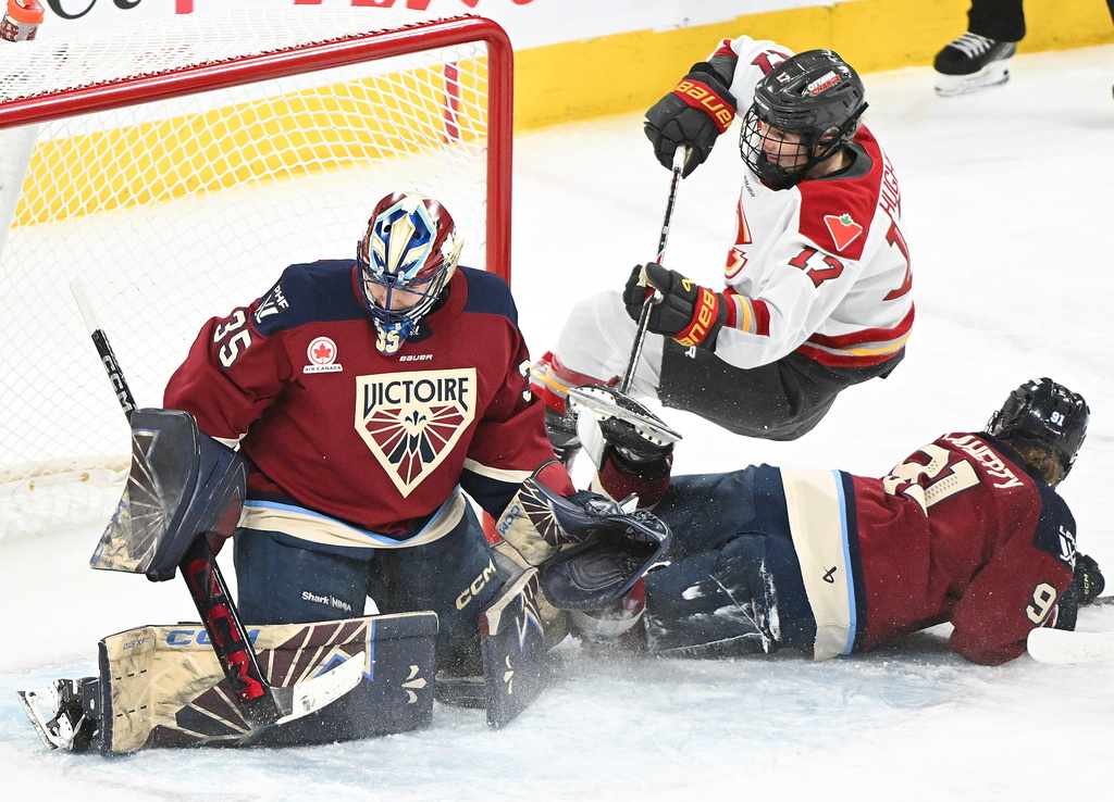 Ottawa Charge's Gabbie Hughes (17) is upended by Montreal Victoire's Maggie Flaherty (91) as she moves in on Victoire goaltender Ann-Renee Desbiens (35) during the second period of an PWHL hockey game in Laval, Que., Saturday, Jan. 24, 2026. (Graham Hughes/The Canadian Press via AP)