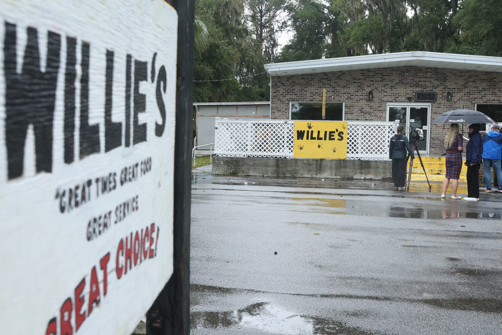 FILE - People stand outside of Willie's Bar and Grill in St Helena Island, S.C., after a shooting occurred early Sunday, Oct. 12, 2025. (AP Photo/Lewis M. Levine, File)