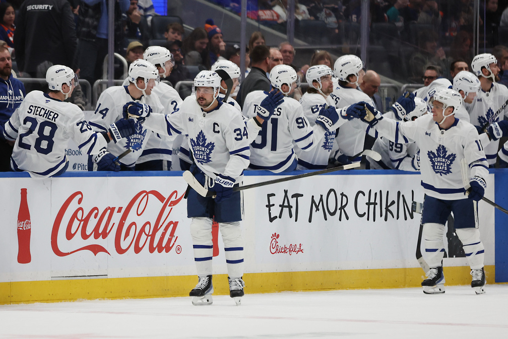 Toronto Maple Leafs center Auston Matthews (34), left, high-fives teammates after scoring during the second period of an NHL hockey game against the New York Islanders, Saturday, Jan. 3, 2026, in Elmont, N.Y. (AP Photo/Heather Khalifa)