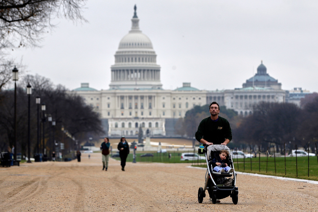 A visitor and his son walk along the National Mall near the Capitol, Wednesday, Nov. 26, 2025, in Washington. (AP Photo/Rahmat Gul)