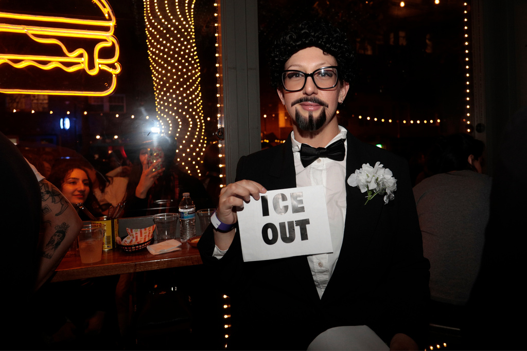 A contestant at the Bad Bunny look-alike contestholds an "ICE OUT" sign throughout the evening at Tacolicious in San Francisco, Thursday, Feb. 5, 2026. (Giselle Garza Lerma/San Francisco Chronicle via AP)