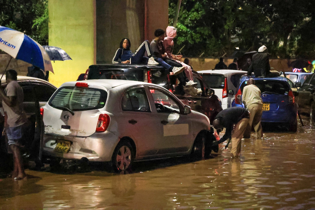 People climb on top of their cars after heavy rains flooded roads in Nairobi, Kenya, on Friday, March 6, 2026. (AP Photo/Andrew Kasuku)