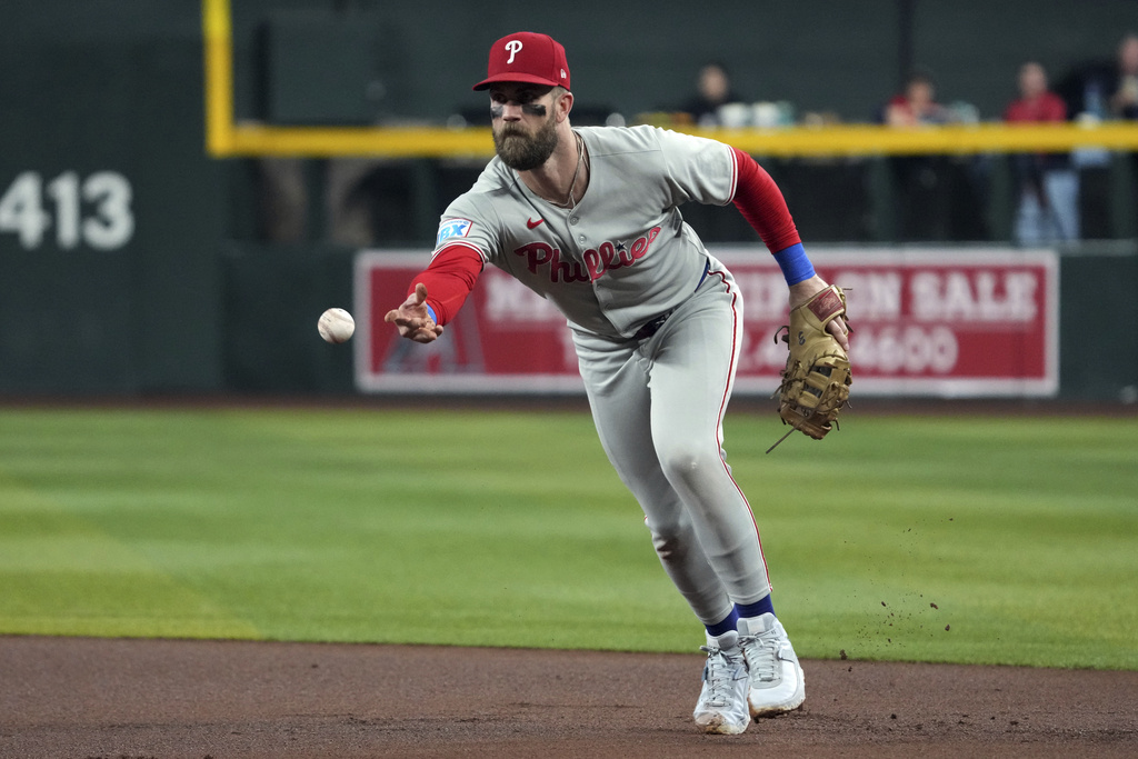 Philadelphia Phillies first base Bryce Harper flips the ball for an out on a ball hit by Arizona Diamondbacks' Ketel Marte in the first inning of a baseball game, Saturday, Sept. 20, 2025, in Phoenix. (AP Photo/Rick Scuteri)