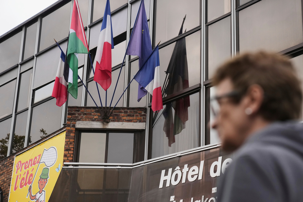 A woman walks past a Palestinian flag set up between French and European flags at the Malakoff's town hall, outside Paris, as France prepares to formally recognize a Palestinian state at the United Nations General Assembly, Sunday, Sept. 21, 2025.(AP Photo/Christophe Ena)