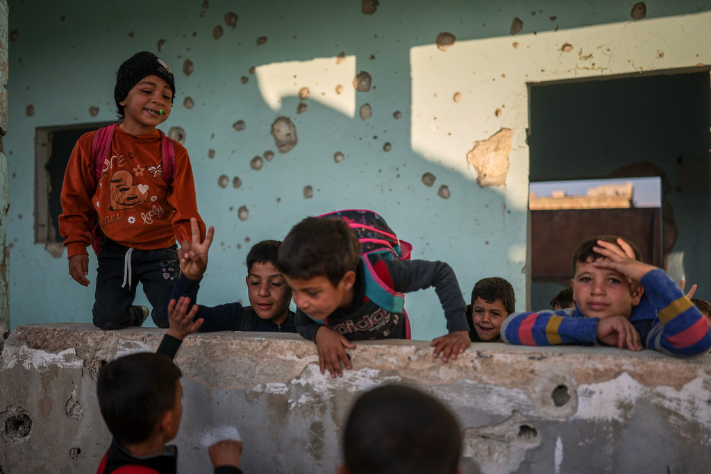 Students play in the courtyard of the Maar Shmarin Primary School, its walls scarred by bullet holes from the fighting between forces loyal to former President Bashar Assad and rebel groups, in the village of Maar Shmarin, in the Idlib countryside, Syria, Sunday, Oct. 19, 2025. (AP Photo/Ghaith Alsayed)