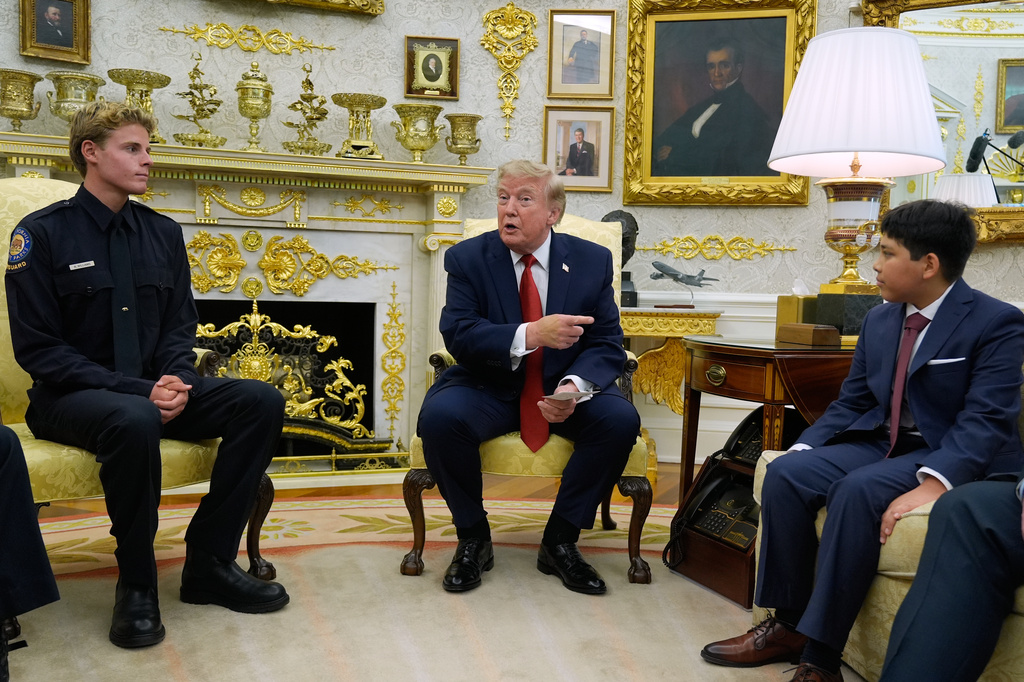 President Donald Trump gestures to Nathaniel Rai, the boy lifeguard Ryder Williams, left, saved as they meet in the Oval Office of the White House, Monday, Aug. 17, 2026, in Washington. (AP Photo/Manuel Balce Ceneta)