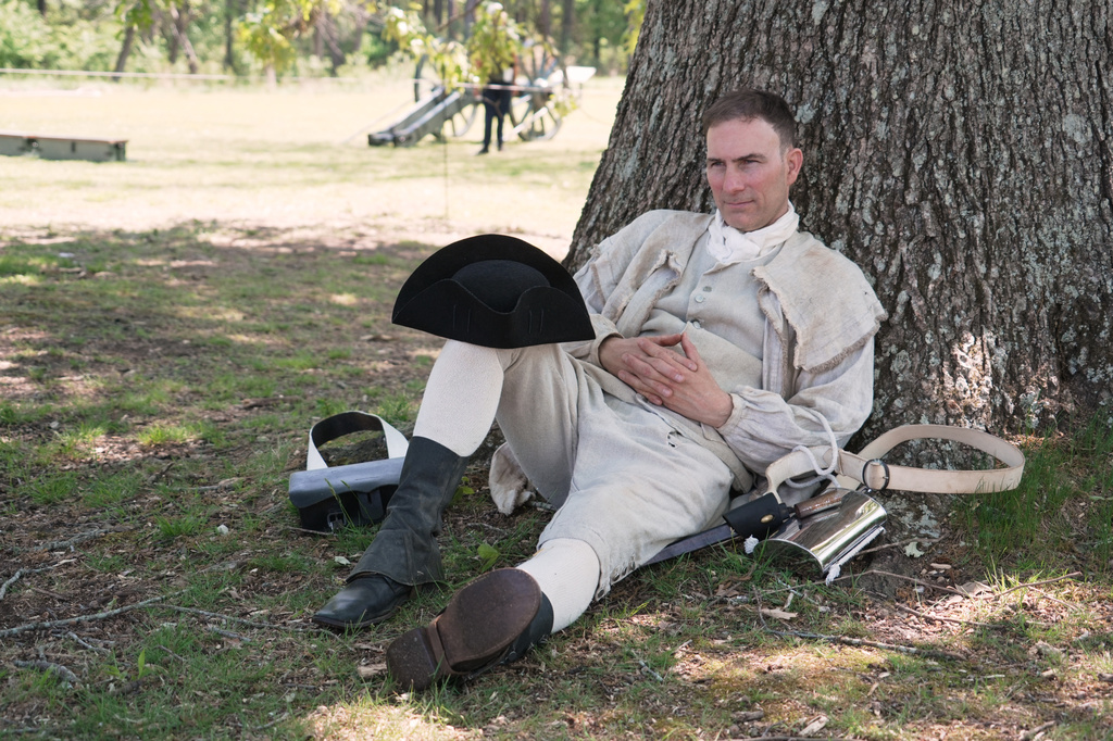 Army officer Jason Monhollen rests beneath a tree during a Revolutionary War event, in which he portrays a private in the 2nd North Carolina Infantry Regiment, in Halifax, N.C., on April 11, 2026. (AP Photo/Allen G. Breed)