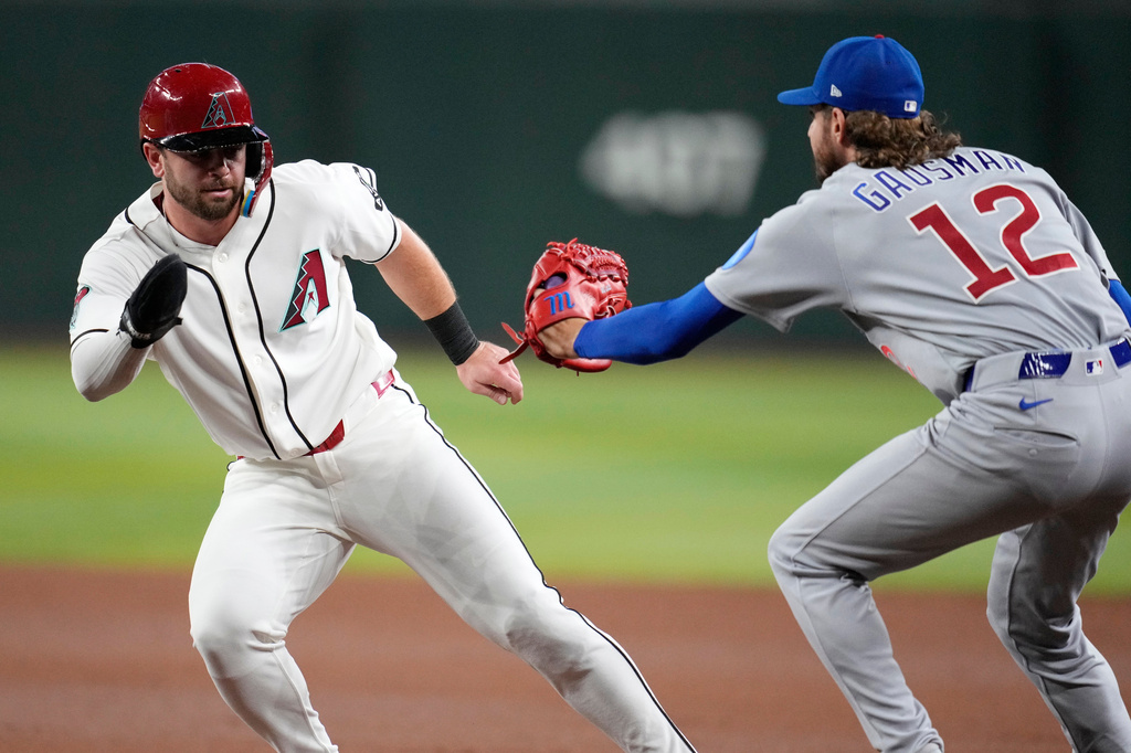 Arizona Diamondbacks' Tim Tawa, left, is tagged out by Chicago Cubs starting pitcher Kevin Gausman (12) during a rundown during the third inning of a baseball game, Monday, Aug. 24, 2026, in Phoenix. (AP Photo/Ross D. Franklin)