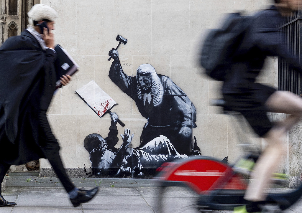 Undated photo released by Banksy of the new artwork by the artist which portrays a judge beating a protester with a gavel at the Royal Courts of Justice in London. (Banksy via AP)