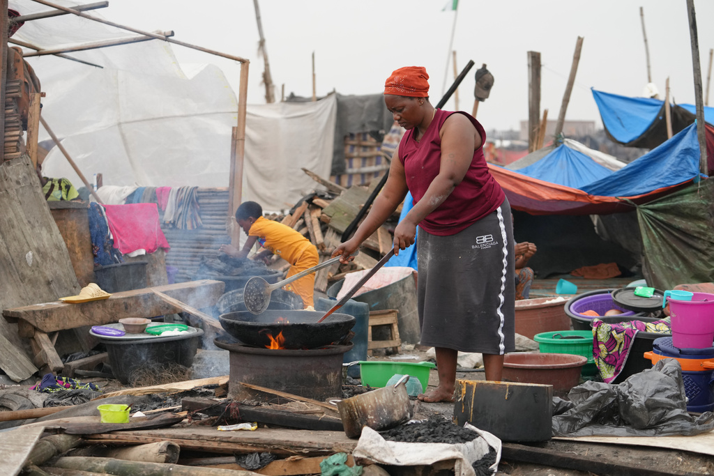 Kpetosi Basra , fried a dough to sell at the ruins of her demolished stills house in Makoko slum in Lagos, Nigeria, Wednesday, Jan. 14, 2026. (AP Photo/Sunday Alamba)