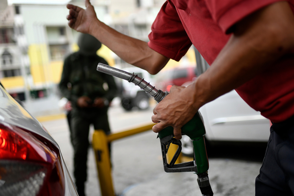 FILE -A worker holds a gas pump at a PDVSA state oil company gas station in Caracas, Venezuela, Monday, May 25, 2020. (AP Photo/Matias Delacroix, File)