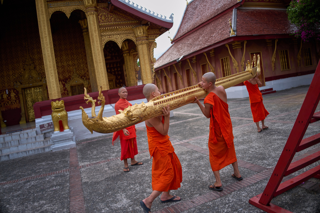 Novice Buddhist monks carry a gilded naga, a mythical serpent in Lao and Buddhist tradition, across the courtyard of a Buddhist temple in Luang Prabang, Laos, after a routine religious ceremony Wednesday, Nov. 5, 2025. (AP Photo/Eugene Hoshiko)