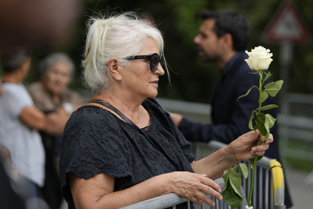 A woman holds a rose outside the San Martino Church in the historic village of Rivalta, about 15 kilometers south of Piacenza, northern Italy, during the funeral of designer Giorgio Armani Monday, Sept. 8, 2025. (AP Photo/Luca Bruno)