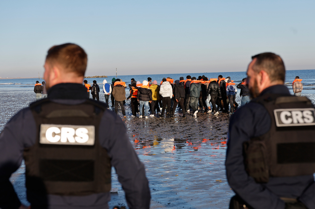 Policemen look at migrants as they board a small boat in an attempt to reach Britain, Wednesday, April 8, 2026 in Malo-les-Bains, northern France. (AP Photo/Jean-Francois Badias)