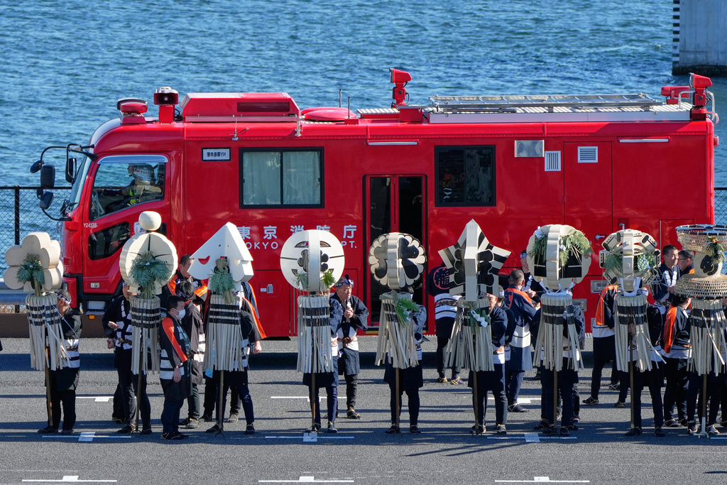 Members of a traditional firefighting preservation group hold a matoi, a traditional flag once used by Edo-period fire brigades as a the latest fire engine past by during the annual New Year's Fire Brigade Review Tuesday, Jan. 6, 2026, in Tokyo. (AP Photo/Eugene Hoshiko)