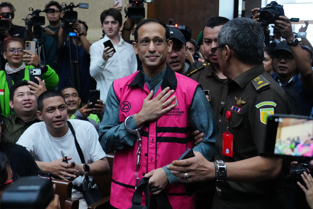 Nadiem Anwar Makarim, center, the co-founder of Indonesia's payments platform and ride hailing company Gojek and former education minister, reacts as he enters the courtroom for his first trial hearing at the Corruption Court in Jakarta, Indonesia, Monday, Jan. 5, 2026. (AP Photo/Tatan Syuflana)